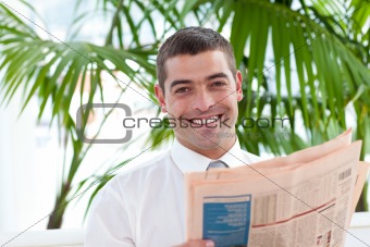 Attractive businessman reading a newspaper in workplace