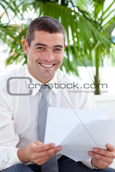 Smiling businessman reading some documents on sofa