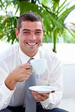 Businessman drinking a cup of coffee on a sofa in workplace