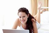 Smiling woman using a laptop in bed