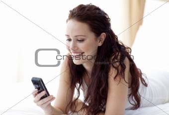 Beautiful woman sending a text in bed