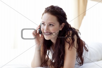 Beautiful woman lying in bed talking on phone