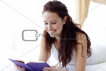 Beautiful woman reading a book in bed