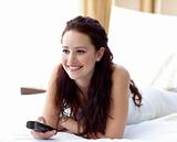 Beautiful woman watching television in bedroom