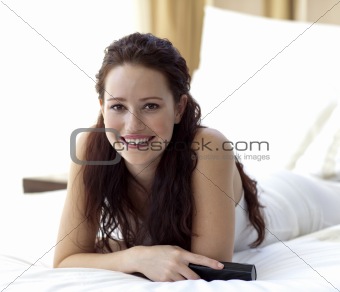Beautiful woman in bed holding a remote control