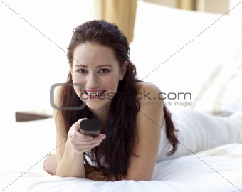 Beautiful woman in bedroom holding a remote control