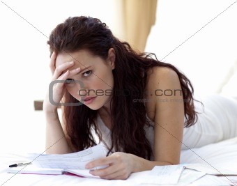 Beautiful woman in bed getting frustrated with bills