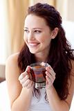 Beautiful woman drinking a cup of tea in bed