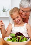 Happy grandmother cooking a salad with granddaughter