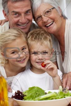 Happy grandparents eating a salad with grandchildren