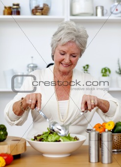Happy senior woman cooking a salad