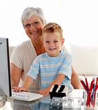 Happy grandson using a computer with his grandmother