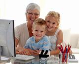 Happy children using a computer with their grandmother
