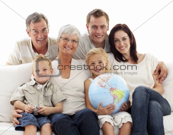 Big family on sofa holding a terrestrial globe