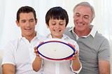 Son holding a rugby ball with his father and grandfather