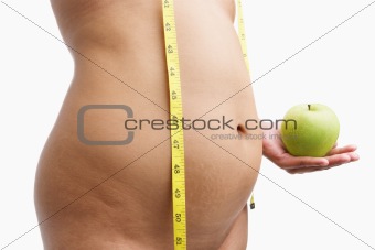 Overweight woman body holding apple with measuring tape