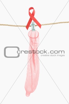 Condom hanging with red ribbon over white background