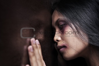 Injured woman leaning sadly on wooden wall