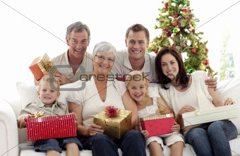 Family holding Christmas presents at home