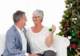 Mature couple sitting on sofa with a Christmas tree