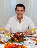 Smiling man eating turkey in Christmas dinner