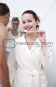 Woman and man cleaning their teeth in bathroom