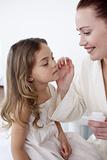 Mother putting cream on her daughter's face
