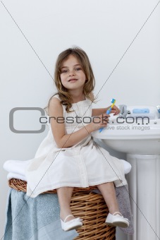 Little girl sitting in bathroom cleaning her teeth