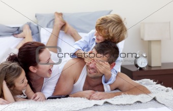 Happy young family having fun in bed