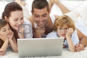 Family in bed playing with a laptop