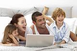 Happy family in bed using a laptop