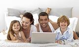 Family in bed using a laptop
