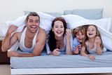 Young family playing in bed together