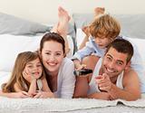 Family relaxing in bed and using a remote