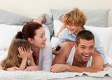 Family lying in bed and son using a remote
