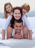 Portrait of happy family having fun in bed