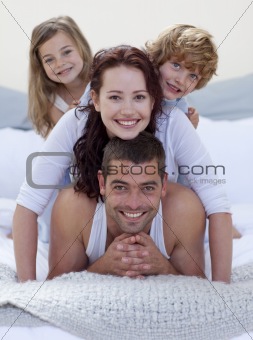 Portrait of happy family having fun in bed
