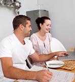 Couple working with a laptop in kitchen