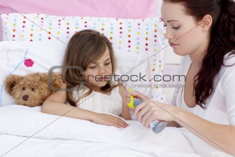 Mother giving sirop to her daughter