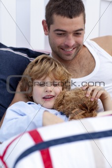 Portrait of father and son reading a book in bed