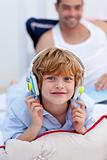 Little boy listening to music in bedroom with headphones on