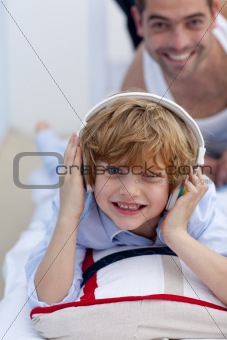 Son listening to music in bed with his father