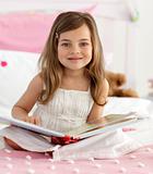 Smiling girl reading a book on the bed