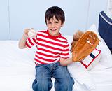 Happy little boy playing baseball in bed
