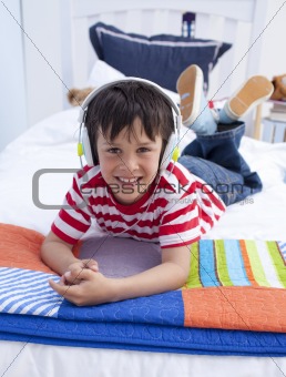 Portrait of boy on headphones listening to music in bed