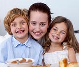 Portrait of children having breakfast with their mother