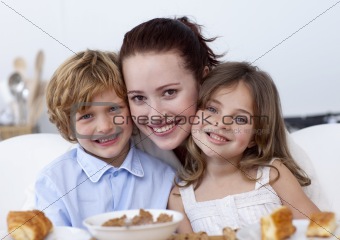 Smiling children having breakfast with their mother