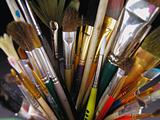 Old paint brushes standing in clear glass cup
