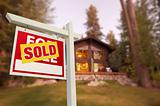 Sold Home For Sale Sign in Front of Beautiful Log Cabin.