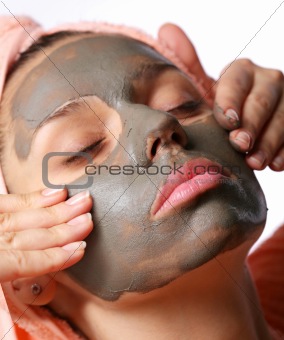 Beauty-spa. Applying of cosmetic mud mask. Close face of young woman